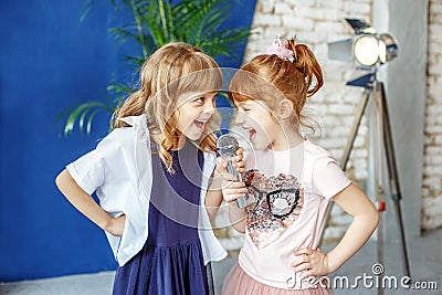 Two happy little children sing a song in karaoke. The concept is Stock Photo