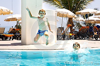 Two happy little kids boys jumping in the pool and having fun on family vacations in a hotel resort. Healthy children Stock Photo