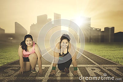 Two overweight women kneeling on the start line Stock Photo