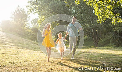 Two happy parents running together with their cute daughter Stock Photo