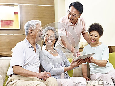 Two happy senior asian couples using tablet computer at home Stock Photo