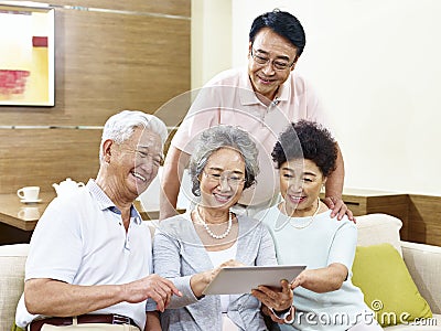 Two happy senior asian couples using tablet computer at home Stock Photo