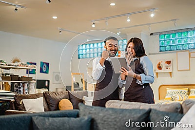 two happy shop clerks as if celebrating something while using a tablet Stock Photo