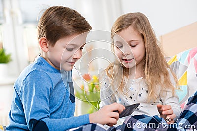 Two happy siblings children having fun and listening music with Stock Photo