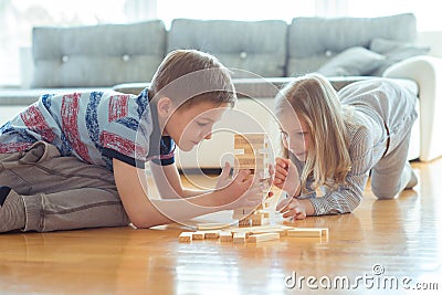 Two happy siblings playing a game with wooden blocks at home Stock Photo