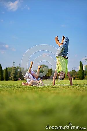 two happy smiling children tumbling on green grass. Cheerful brother and sister laugh together. Happy kids have fun on Stock Photo
