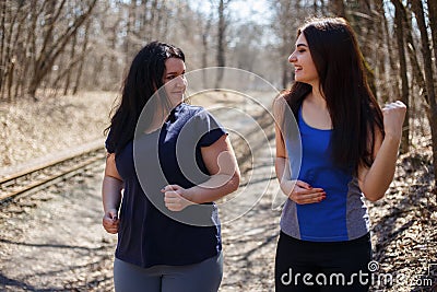 Two happy smiling fit and overweight women friends jogging in th Stock Photo