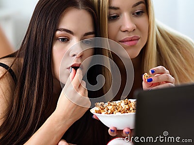 Two happy smiling girlfriends eat popcorn in bed Stock Photo