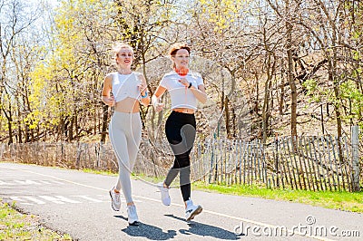 Two happy sporty girls running in the park Stock Photo