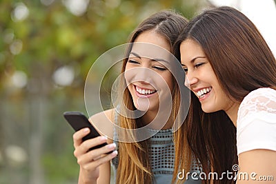 Two happy women friends sharing a smart phone Stock Photo