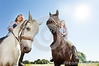 Two happy women riding beautiful purebred horses Stock Photo