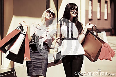 Two happy fashion women with shopping bags walking in city street Stock Photo