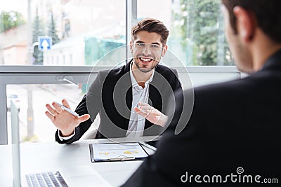 Two happy young businessmen sitting and working on business meeting Stock Photo