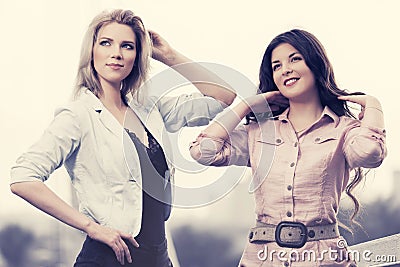 Two happy young fashion women walking on city street Stock Photo