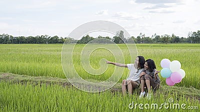 Two happy young girl siting at beautiful field rice, Nature background Stock Photo