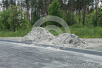 Two heaps of white sand on gray asphalt on the street Stock Photo