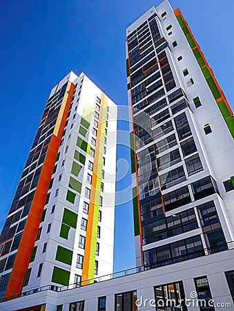 Two high-rise multi-colored apartment complexes on a blue sky background Stock Photo