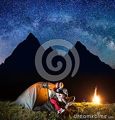 Two hikers having a rest in his camp at night near campfire under shines starry sky Stock Photo