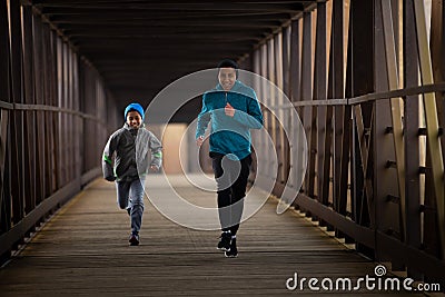 Two Hispanic Brothers Run A Race Down Bridge Stock Photo