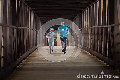 Two Hispanic Brothers Run A Race Down Bridge Stock Photo