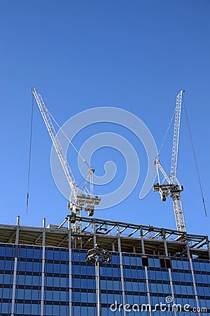 Two hoisting tower crane on the top of being construction of modern high skyscraper building Editorial Stock Photo