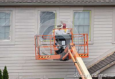 Home painters using paint spray from boom lift Stock Photo