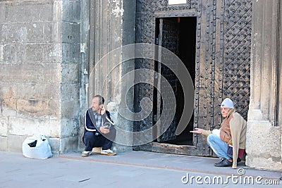 Two homeless people earn their living by begging at church doors Editorial Stock Photo