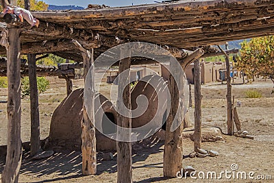 Two hornos-traditional earthen ovens- underneath a drying rack with a childs doll left on the corner - Homes of the Ute Pueblo in Stock Photo