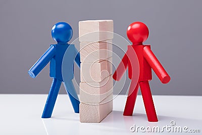 Two Human Figures Separated By Wooden Blocks Stock Photo