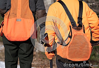 Two Hunters Walking with Shotguns and Tail Feathers Sticking Out of Their Pouch. Editorial Stock Photo