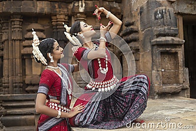 Two Indian classical odissi dancers striking pose against the backdrop of Mukteshvara Temple with sculptures in bhubaneswar, Odish Stock Photo