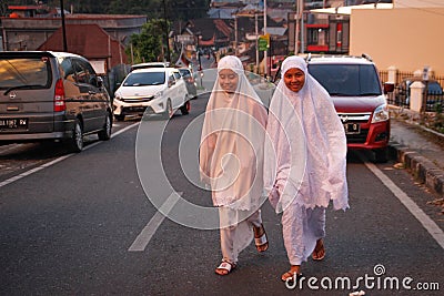 Two Indonesian girls are walking on a city street in white clothes and hijab Editorial Stock Photo