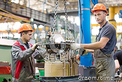 Two industrial workers assembling power transformer at conveyor factory workshop Stock Photo