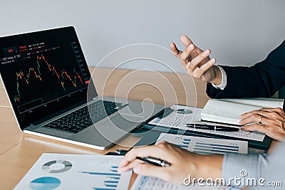 Two investors working together are analyzing the stock chart on the computer screen at the company Stock Photo