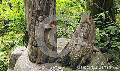 Two Japanese wood carving of a goddess and Buddha in a green forest. Stock Photo