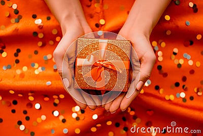 two joined hands holding a golden gift box with glittering ribbons, symbolizing gratitude and affection, human connection through Stock Photo