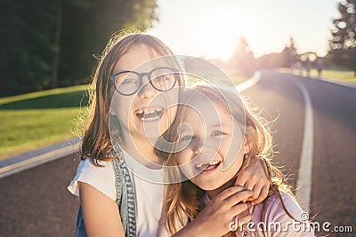 Two joyfull girls hugging and smiling against the sunset. Stock Photo