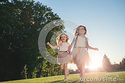 Two joyfull girls running against the sunset. Stock Photo