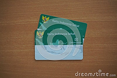 Two Kartu Indonesia Sehat or KIS (Indonesia Government Health Insurance card) on a wooden table. Editorial Stock Photo