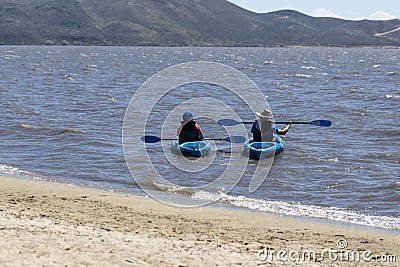 Two kayakers paddling on a windy day close to the beach at Washoe Lake Editorial Stock Photo