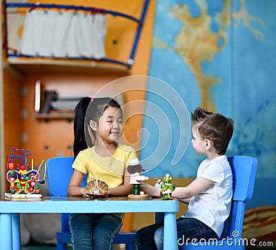 Two kids boy and girl sit at the table and play toy doctors and chat Stock Photo