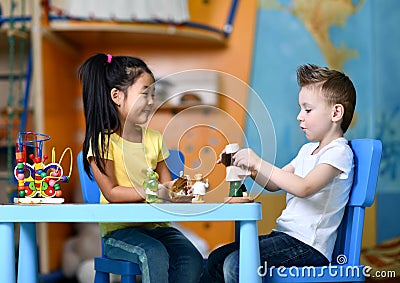 Two kids boy and girl sit at the table and play toy doctors Stock Photo