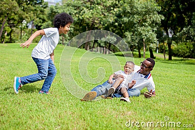 Two kids chasing and playing together while dad caught a boy in Stock Photo