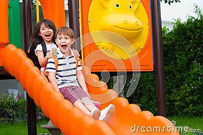 Two kids friends having fun to play together on children`s slide at school playground,back to school activity Stock Photo