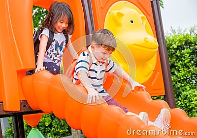 Two kids friends having fun to play together on children`s slide Stock Photo