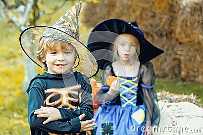 Two kids like skeleton or witch Ready for Trick or Treat. Surprised group little zombie in Halloween costume eating Stock Photo