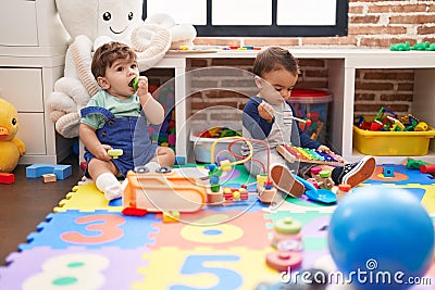 Two kids playing xylophone and tambourine sitting on floor at kindergarten Stock Photo