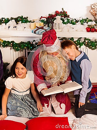 Two kids sitting with Santa reading book Stock Photo