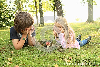 Two kids watching red toadstool Stock Photo