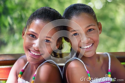Two of a kind. Cropped portrait of two twin sisters sitting on a park bench. Stock Photo